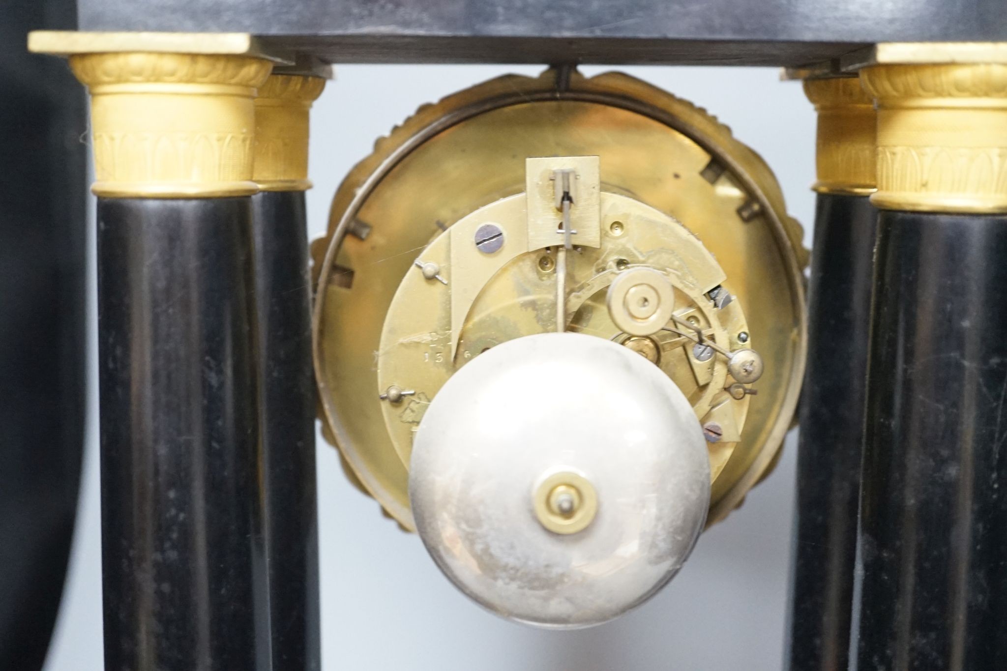 A 19th century French ebonised portico mantel clock with brass mounts, 47 cms high.